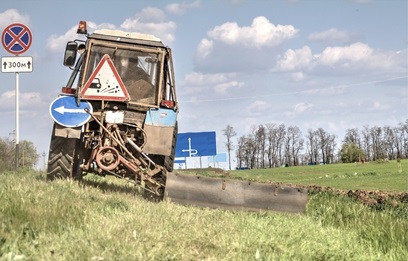 A highway mower mowing grass in a ditch