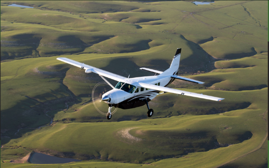A small airplane flying over hills